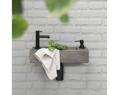 Wastafel met kraan en zeepdispenser aan een muur