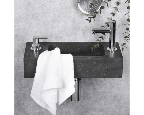 Stenen wastafel met kraan, zeepdispenser en handdoek