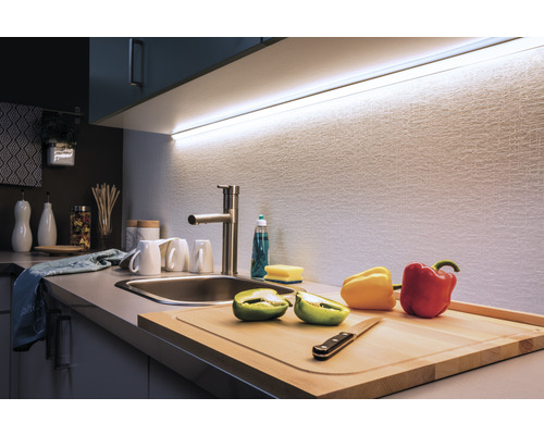 Keukenscène met spoelbak, kraan, snijplank en ledlamp onder de bovenkast