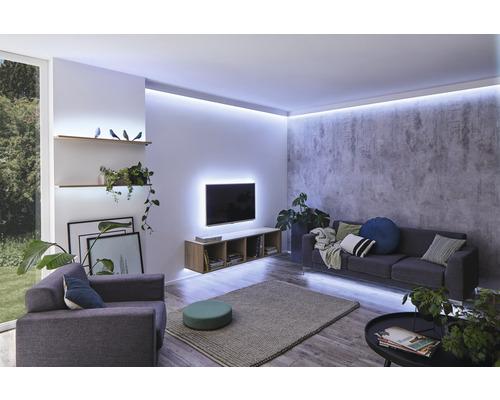 Woonkamer met bank, fauteuil, televisie en indirecte verlichting.