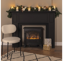 Decoratieve haard met decoratie, cadeaus, fauteuil en vloerkleed in een woonkamer