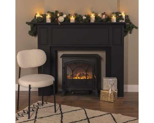 Decoratieve haard met decoratie, cadeaus, fauteuil en vloerkleed in een woonkamer