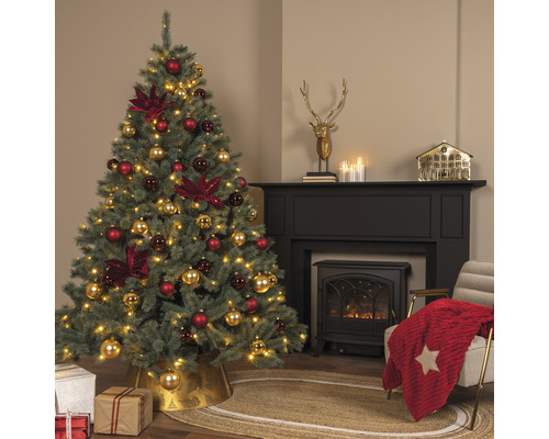 Kerstboom met rode en gouden kerstornamenten in een woonkamer met open haard