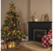 Feestelijk versierde kerstboom naast een open haard met decoraties en geschenken