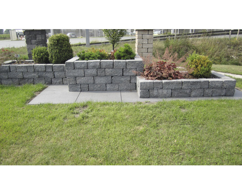 Ontwerpidee met straatstenen voor een tuinmuur met beplanting