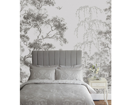 Slaapkamer met bed voor een behang met boom- en vogelmotieven.