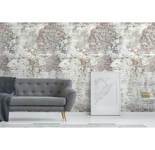 Woonkamer met grijze bank voor een behang dat een afbrokkelende bakstenen muur imiteert.