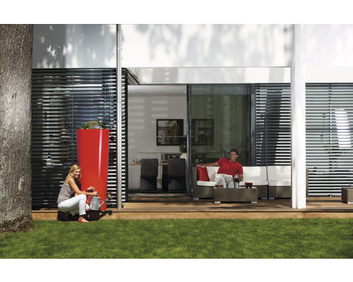 Scene met een hoge regenwatertank, een vrouw met een gieter en een man op een terrasbank