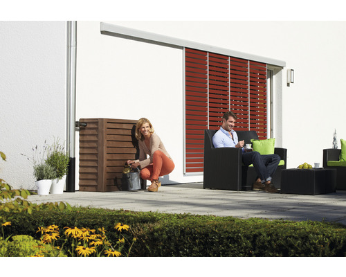 Scene met een vrouw die water schept uit een regenwatertank en een man die in een tuinstoel zit