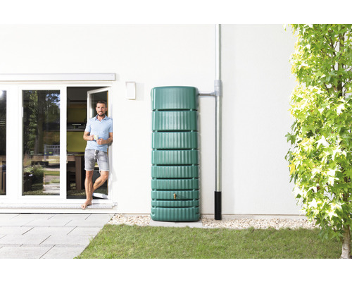 Regenwatertank van kunststof naast de muur van het huis met regenpijp