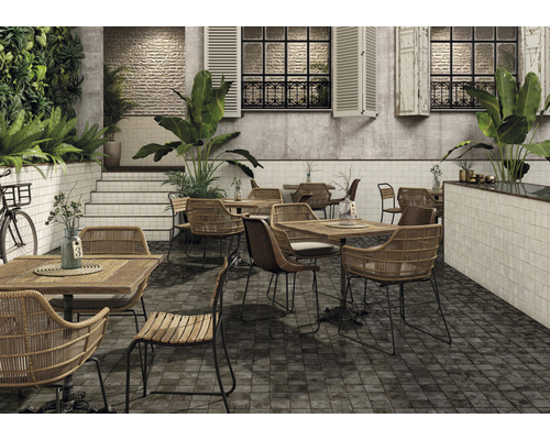 Restaurantterras met tafels, stoelen, planten en een tegelvloer.