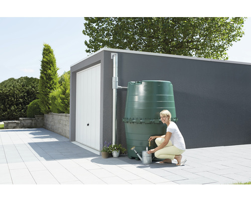 Vrouw vult gieter bij een groene regenwatertank voor een garage