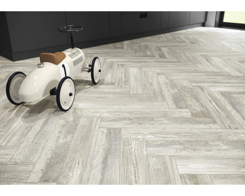 Vloer met lichte tegels in visgraatmotief en speelgoedauto