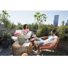 Scene met vrouw op terrasbank en man in fauteuil op een dakterras met tafel en planten