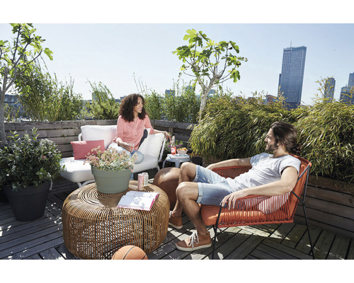 Scene met vrouw op terrasbank en man in fauteuil op een dakterras met tafel en planten