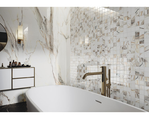 Lichte badkamer met bad, wastafel en tegels met marmerlook