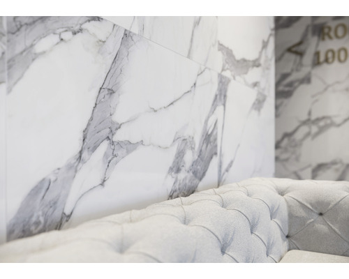 Wandtegels in marmerlook en een bank in de kamer.