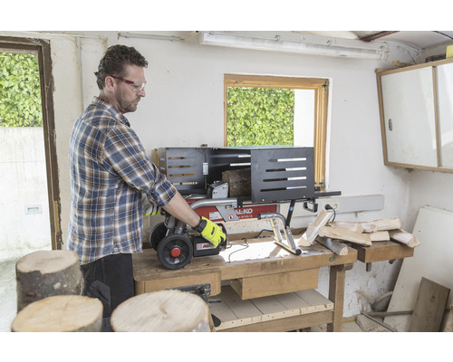 Een man bedient een houtklover op een werkbank om hout te kloven.