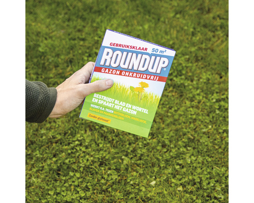 Roundup Gazon Onkruidvrij verpakking in hand op gazon achtergrond