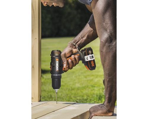 Een man boort met een accuschroevendraaier een gat in een houten plank.