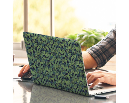 Een laptop met een tropisch bladerpatroon wordt door iemand gebruikt