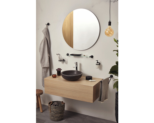 Moderne badkamer met wastafel, ronde spiegel en stijlvolle accessoires.