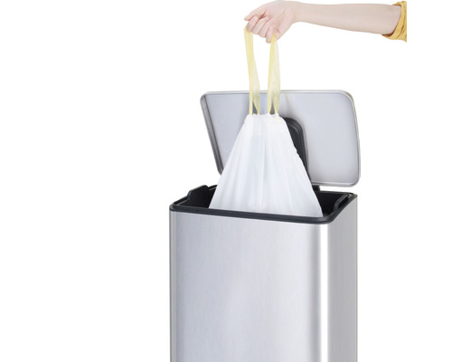 Een afvalemmer met een volle vuilniszak die door een hand wordt opgetild