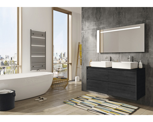 Badkamer met bad, wastafel, spiegel, radiator en vloerkleed in een lichte en ruime uitvoering