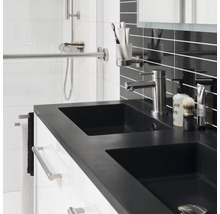 Moderne badkamer met dubbele wastafel, kraan en opbergruimte voor badkameraccessoires.