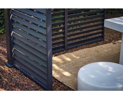 Detailopname van een modern privacyscherm met horizontale lamellen in een tuinomgeving.