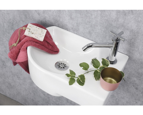 Bovenaanzicht van een keramische wastafel met kraan, handdoek en zeep.