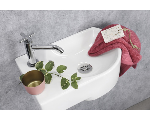 Detailopname van een witte wastafel met kraan, zeep, handdoek en decoratie