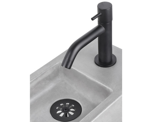 Wastafelkraan in het zwart op een betonnen wastafel met afvoergarnituur