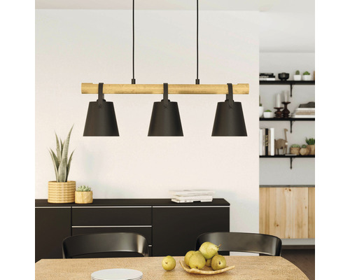 Hanglamp met drie lampen en houten detail boven een eettafel