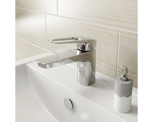 Glanzende wastafelmengkraan op een wastafel met zeepdispenser.