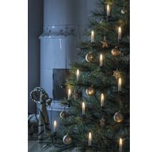 Kerstboom met kaarsen en ornamenten, open haard op de achtergrond