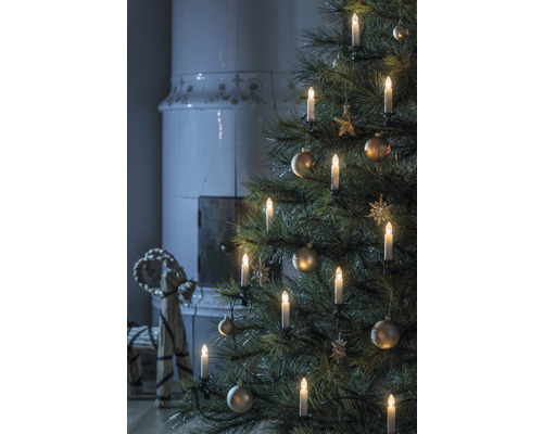 Kerstboom met kaarsen en ornamenten, open haard op de achtergrond