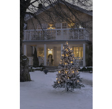 Besneeuwde kerstboom met kaarsen voor een huis in de winter