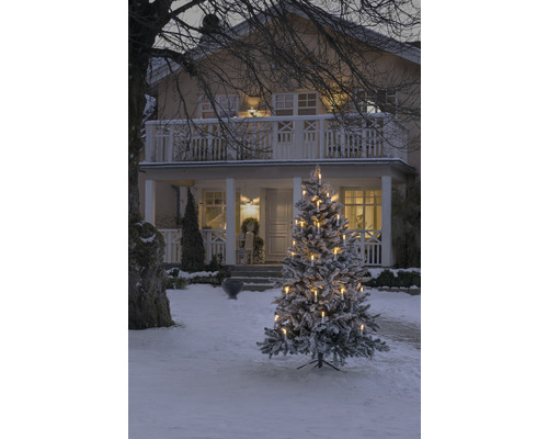 Besneeuwde kerstboom met kaarsen voor een huis in de winter