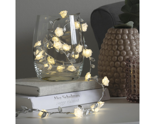 Decoratieve lichtslinger met rozen en bladeren in een glas