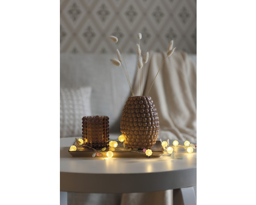 Decoratie met vaas, theelichthouder en lichtslinger op een tafel