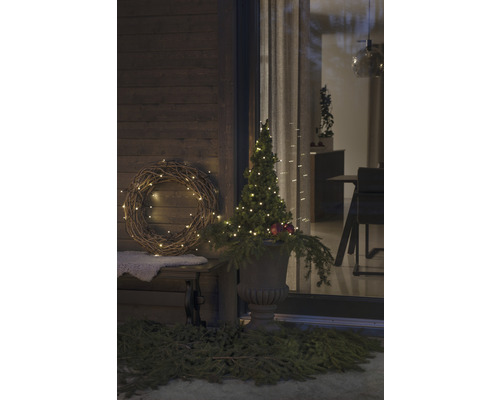 Gedecoreerde veranda met verlichte krans en boom in vaas