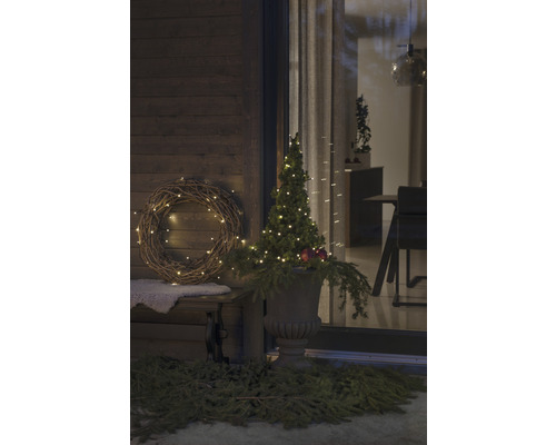 Gedecoreerde veranda met krans, verlichte boom en plantenbak