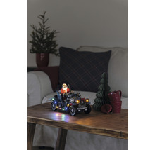 Decoratief kersttafereel met kerstman in oldtimer, verlicht, op een houten tafel.