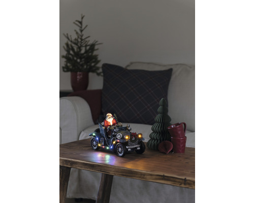 Decoratief kersttafereel met kerstman in oldtimer, verlicht, op een houten tafel.