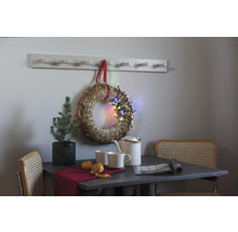 Decoratief interieur met strokrans, lichtsnoer, wandkapstok, tafel, stoel en theeservies.