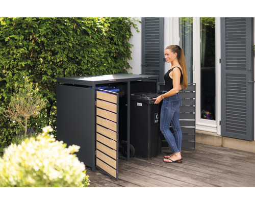 Afvalcontainerbox in de tuin met een vrouw die een afvalcontainer plaatst