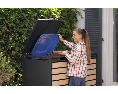 Vrouw vult grijze afvalbak met een blauwe vuilnisbak en karton