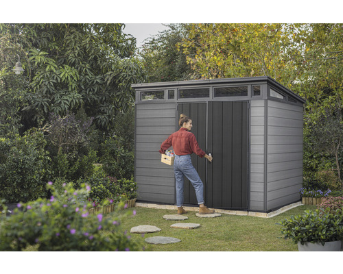 Tuinscene met tuinhuis en vrouw die een kist draagt