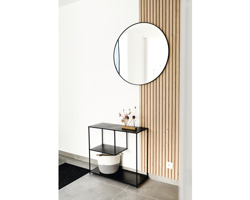 Entree met ronde spiegel, zwarte consoletafel en houten wandpanelen voor een moderne woonambiance.